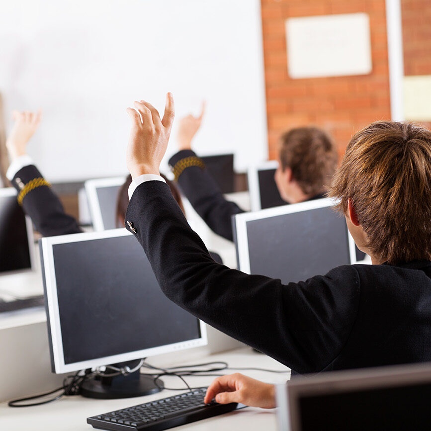 group of high school students hands up in computer class